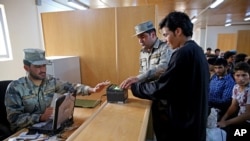 FILE - Afghan border police officers help a returnee scan fingerprints at the Afghanistan-Iranian border on the outskirts of Islam Qala in Herat province, west of Kabul, Afghanistan, April 13, 2015.