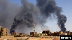 FILE PHOTO: Man walks while smoke rises above buildings after aerial bombardment in Khartoum North. REUTERS/Mohamed Nureldin Abdallah/File Photo