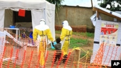 FILE - Health workers walk with a boy suspected of having been infected with the Ebola virus, at an Ebola treatment center in Beni, eastern DRC, Sept 9, 2018.