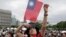A person poses with Taiwan's national flag for a photo during National Day celebrations in front of the Presidential Building in Taipei, Taiwan, Oct. 10, 2024. 