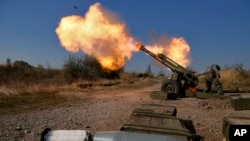 FILE - Pro-Russian rebels fire artillery toward Ukrainian position at Donetsk Sergey Prokofiev International Airport on the outskirts the city of Donetsk, eastern Ukraine, Oct. 14, 2014.