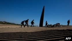 Migrantes de Centroamérica cruzan la frontera por el muro que separa a Estados Unidos de México luego de entregarse a las autoridades el 12 de mayo de 2021 en Yuma, Arizona.