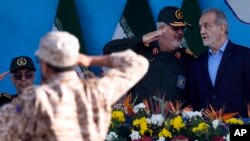 FILE - Iranian President Masoud Pezeshkian, right, listens to commander of the Revolutionary Guard's ground force Gen. Mohammad Pakpour during an annual armed forces parade just outside Tehran, Iran, Sept. 21, 2024. 
