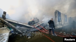 FILE - Firefighters inspect the grounds after a fire at a storage site in Baghdad that housed the boxes from Iraq's May parliamentary election, Iraq, June 10, 2018. 