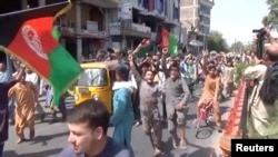 Orang-orang membawa bendera Afghanistan dalam aksi protes anti-Taliban di Jalalabad, Afghanistan, 18 Agustus 2021 dalam tangkapan layar yang diambil dari sebuah video. (Pajhwok Afghan News/Handout via REUTERS)
