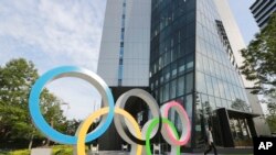A man walks past the Olympic rings in Tokyo, Monday, June 7, 2021. (AP Photo/Koji Sasahara)