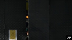 Una empleada de una tienda mira desde la entrada mientras espera que lleguen los clientes, en Caracas, el 29 de agosto 29 de 2020. [Foto: AP]