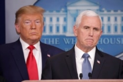 President Donald Trump, left, listens to Vice President Mike Pence, right, as he pauses while speaking to members of the media to address the nation about the coronavirus threat.