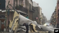 A man passes by a section of roof that was blown off of a building in the French Quarter by Hurricane Ida winds, Aug. 29, 2021, in New Orleans.