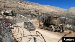 Israeli soldiers ride in a military vehicle along the ceasefire line with Syria and the Israeli-occupied Golan Heights, as seen from the Golan Heights, Dec. 15, 2024. 