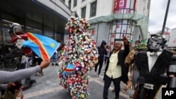 A man marches between two artists dressed in costume as they participate in celebrations marking the 60th anniversary of Congo's independence from Belgium in the Brussels district of Matonge, June 30, 2020. 
