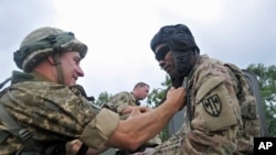 US and Ukrainian servicemen talk during the opening ceremony for the Rapid Trident/Saber Guardian 2015 military exercises at the International Peacekeeping and Security Center base outside Lviv, Ukraine, July 20, 2015.