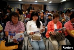 FILE - People wait in line at a health insurance enrollment event in Cudahy, California, March 27, 2014.