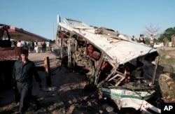 FIL E- Afghans and security forces inspect damage to a bus after a suicide attack in Jalalabad east of Kabul, Afghanistan, April 11, 2016.
