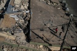Boys walk on the roof of a destroyed house after an earthquake in the city of Darbandikhan, northern Iraq, Nov. 13, 2017.