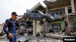 A member of the Iraqi Federal Police walks next to a destroyed house after their clashes with the Islamic State fighters in western Mosul, Iraq.