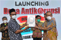 Kepala Desa Panggungharjo, Bantul, DI Yogyakarta, Wahyudi Anggoro Hadi menerima plakat dari Ketua KPK Alexander Marwata. (Foto: Courtesy/Kemendes PDTT)