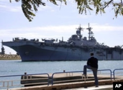 An Egyptian watches US amphibious assault ships USS Kearsarge as it sails at the Suez canal in Ismailia , Egypt, March 2, 2011