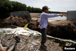 Village leader Matakin Bondien inspects a stream of wastewater discharged from the Sunlight Seafood shrimp farm in Pitas, Sabah, Malaysia, July 6, 2018.