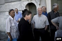 Pensioners wait outside a branch of the National Bank of Greece to get their pensions on June 29, 2015 in Athens.