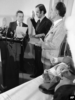 FILE - Four-year-old Beau Biden, foreground, plays near his father, Joe Biden, center, as he is sworn in as the U.S. senator from Delaware, by Senate Secretary Frank Valeo, left, in ceremonies in a Wilmington hospital, Jan. 5, 1973. Beau was injured in an accident that killed his mother and sister in December 1972.