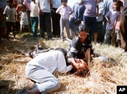 FILE - An unidentified suspected thief lies dead on the ground as his relatives grieve over his body in the midst of a mob that had beaten him to death, in a southern district of Phnom Penh, Cambodia, April 11, 2002.