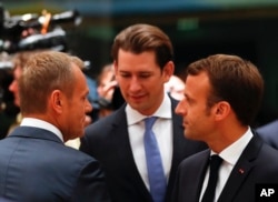 FILE - European Council President Donald Tusk, left, speaks with Austrian Chancellor Sebastian Kurz, center, and French President Emmanuel Macron during a round table meeting at an EU summit in Brussels, Oct. 17, 2018.