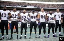 Baltimore Ravens players link arms during the playing of the U.S. national anthem before an NFL football game against the Jacksonville Jaguars at Wembley Stadium in London, Britain, Sept. 24, 2017.