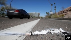 A vehicle goes by the scene of Sunday's fatality where a pedestrian was stuck by an Uber vehicle in autonomous mode, in Tempe, Ariz., Monday, March 19, 2018. (AP Photo/Chris Carlson)