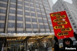 FILE - A protester holds a sign up during a #MeToo demonstration outside Trump International Hotel in New York City, Dec. 9, 2017.