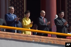 FILE - Chinese President Xi Jinping, right, applauds with, from left, Kazakhstan President Nursultan Nazarbayev, South Korea President Park Geun-hye and Russia's President Vladimir Putin, during a parade to mark the 70th anniversary of Japan's surrender.