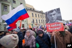 FILE - People march in memory of opposition leader Boris Nemtsov, portrait at right, in Moscow, Russia, Feb. 26, 2017. Thousands of Russians take to the streets of downtown Moscow to mark two years since Nemtsov was gunned down outside the Kremlin.