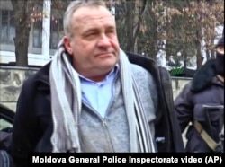 Valentin Grossu is escorted by an armed police officer following his arrest during a cesium smuggling sting operation in Chisinau, Moldova, Feb. 19, 2015.