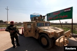 FILE - Iraqi army members stand guard at the entrance to the Nineveh Liberation Operations Command at Makhmour base, south of Mosul, Iraq, March 13, 2016.