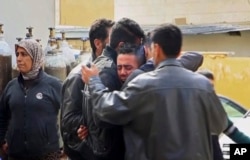 FILE - Men grieve outside a hospital following Turkish airstrikes on the Syrian Kurdish enclave of Afrin, northwestern Syria, Feb. 14, 2018.