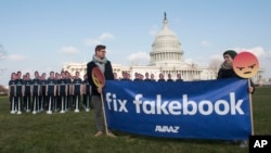 Avaaz campaigners hold a banner in front of 100 cardboard cutouts of Facebook CEO Mark Zuckerberg outside the U.S. Capitol in Washington, April 10, 2018, ahead of his Senate testimony.