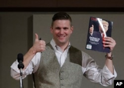 Richard Spencer holds a magazine cover showing then-President-elect Donald Trump before signing it for a supporter, Dec. 6, 2016, in College Station, Texas.