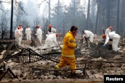 A volunteer search and rescue crew from Calaveras County comb through a home destroyed by the Camp Fire in Paradise, California, Nov. 13, 2018.