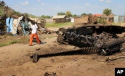 FILE - A man walks past the remains of a tank destroyed during fighting between government and rebel forces on July 10, 2016, in the Jebel area of the capital Juba, South Sudan, July 16, 2016.