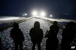 FILE - Military veterans stand on a bridge across from police protecting the Dakota Access oil pipeline site in Cannon Ball, N.D., Dec. 1, 2016.