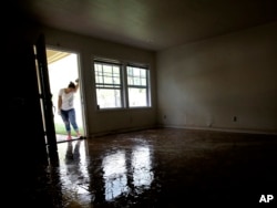 FILE - Alejandra Castillo takes a break from carrying water-soaked items out of her family's home after flood waters receded in Houston, Aug. 31, 2017.