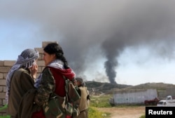 FILE - A Kurdistan Workers' Party (PKK) fighter looks toward a position hit by Islamic State car bombs in northwest Iraq, March 11, 2015.
