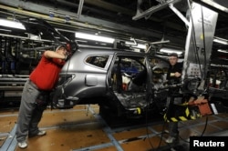 FILE - Nissan technicians work on a Qashqai car on the production line at the company's plant in Sunderland, Britain, Nov. 9, 2011.