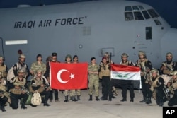 Turkish and Iraqi soldiers hold their national flags after the arrival of Iraqis in Silopi, near the Habur border gate with Iraq, southeastern Turkey, Sept. 25, 2017.