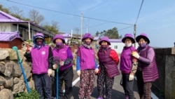 Jung Soon-shim, 88, and other residents dressed in purple clothing pose for a photograph at the Purple Island in Shinan, South Korea, March 8, 2021. Picture taken March 8, 2021. REUTERS/Minwoo Park