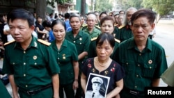 A woman holds a portrait of General Giap outside the National Funeral House in Hanoi, Oct. 12, 2013.