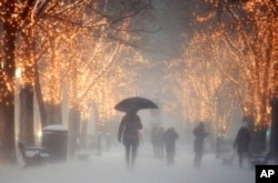 People walk through the Commonwealth Avenue Mall during a winter storm in Boston, Jan. 7, 2017. A storm that wreaked havoc along the East Coast arrived in southern New England Saturday, bringing blizzard conditions to some areas and making travel treacherous.