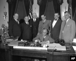 FILE - President Franklin D. Roosevelt signs the Industrial Control-Public Works Bill at the White House, June 16, 1933.
