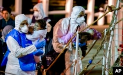 Rescuers help children disembark in the Sicilian harbor of Pozzallo, Italy, April 20, 2015. About 100 migrants, including 28 children, were rescued on Sunday by a merchant vessel in the Sicilian Strait while they were trying to cross.