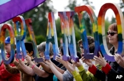 Members of Capital City Pride and others from the LGBT community hold up letters spelling out "Orlando" to honor of the recent shooting at a gay nightclub days earlier before the raising of a rainbow flag in front of the Washington state Capitol, June 15, 2016.